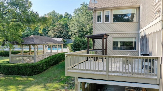 wooden deck featuring a lawn, a gazebo, and a pool