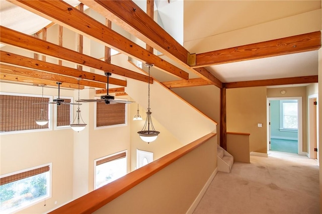 hallway with beamed ceiling and light colored carpet