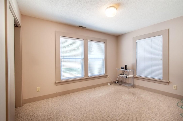 carpeted empty room featuring a textured ceiling