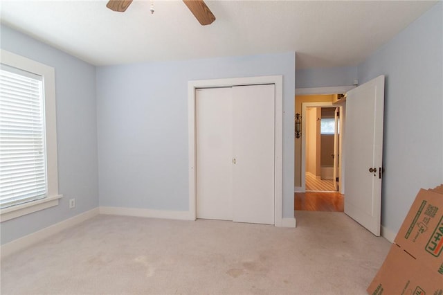 unfurnished bedroom featuring ceiling fan, a closet, and light colored carpet