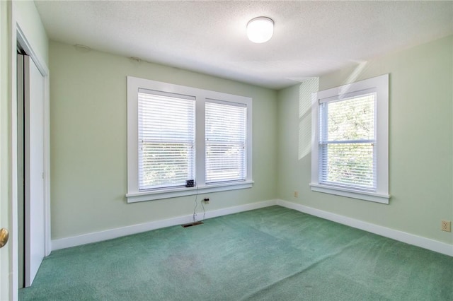 unfurnished room featuring a wealth of natural light, light carpet, and a textured ceiling