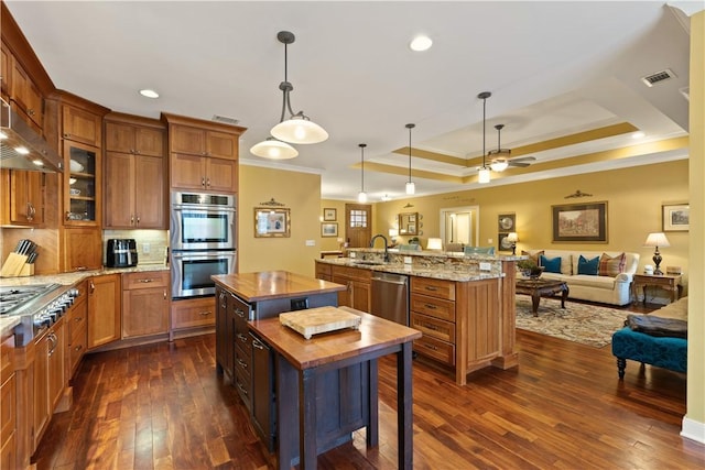 kitchen with butcher block counters, a center island, appliances with stainless steel finishes, dark hardwood / wood-style flooring, and pendant lighting