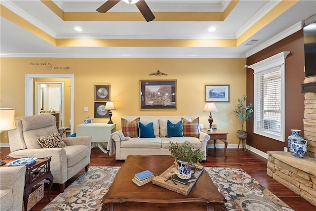 living room featuring ceiling fan, ornamental molding, a tray ceiling, and dark hardwood / wood-style flooring