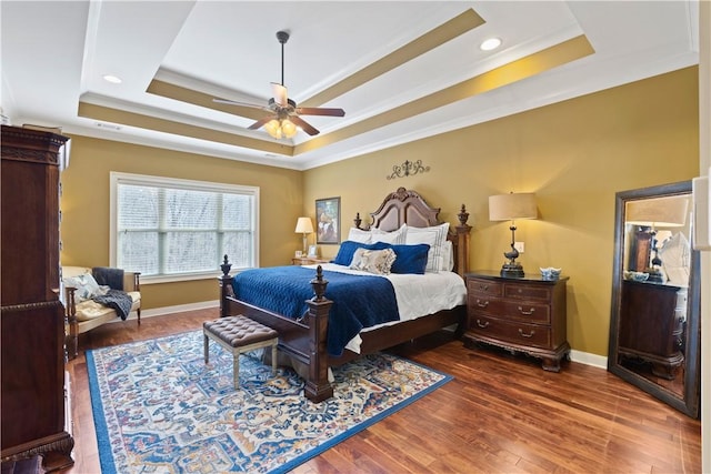 bedroom with crown molding, ceiling fan, dark hardwood / wood-style flooring, and a raised ceiling