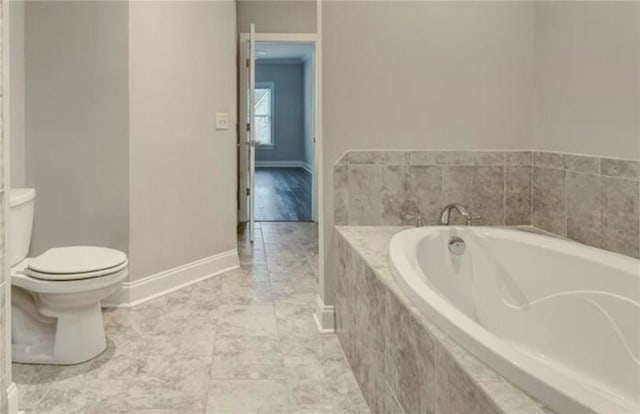 bathroom with tiled tub and toilet