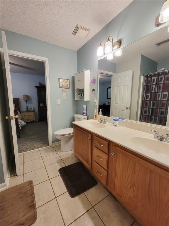 2580 Lee Road 148, Opelika, AL 36804 - full bath featuring tile patterned floors, toilet, double vanity, a textured ceiling, and a shower with curtain