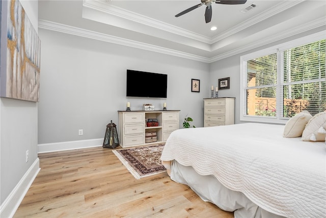 bedroom with a tray ceiling, light hardwood / wood-style flooring, ceiling fan, and crown molding