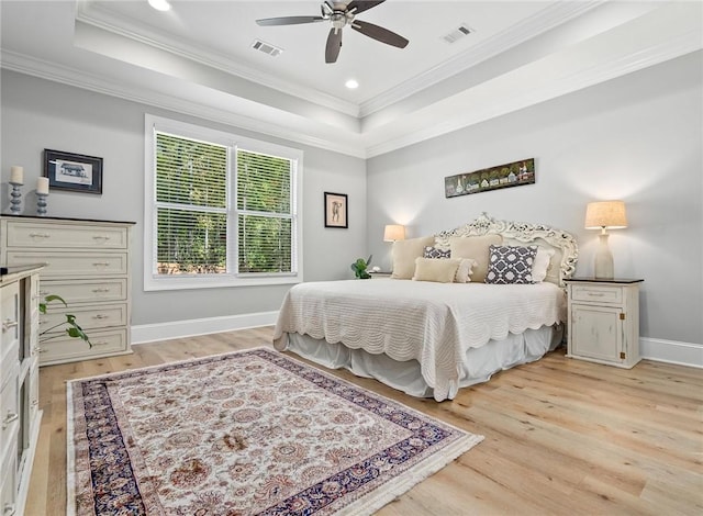 bedroom featuring light wood-type flooring, a raised ceiling, and ceiling fan