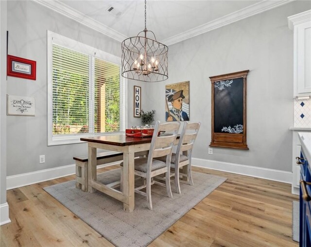 dining space featuring crown molding, light hardwood / wood-style floors, and an inviting chandelier