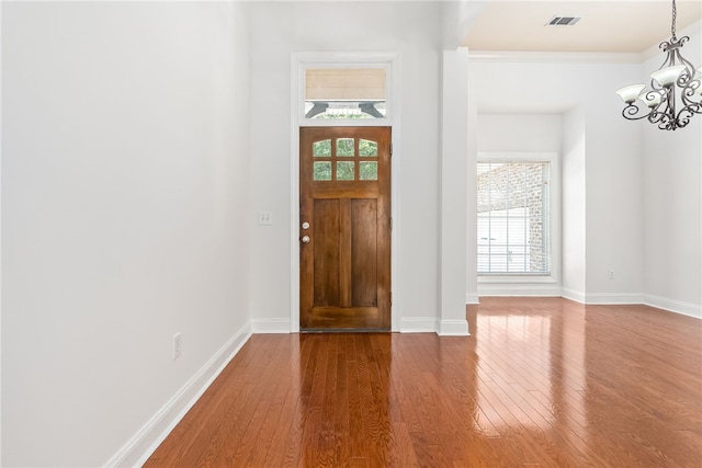 entrance foyer with a wealth of natural light, hardwood / wood-style floors, and a chandelier