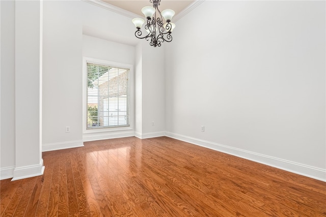 unfurnished room featuring hardwood / wood-style floors, an inviting chandelier, and crown molding