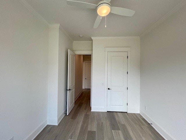 unfurnished bedroom with hardwood / wood-style flooring, ornamental molding, and ceiling fan
