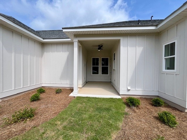 view of exterior entry with a yard and a patio