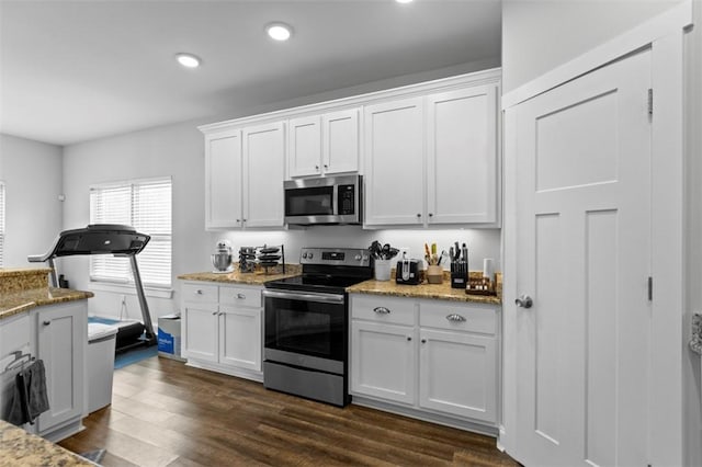 kitchen with dark wood-type flooring, appliances with stainless steel finishes, light stone countertops, and white cabinets