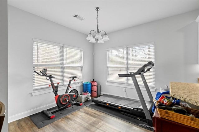 workout room featuring hardwood / wood-style flooring and an inviting chandelier