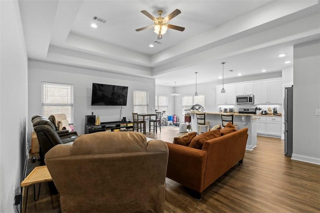 living room featuring a raised ceiling, dark hardwood / wood-style floors, a wealth of natural light, and ceiling fan