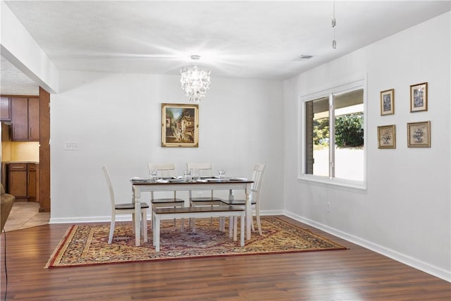 dining area featuring visible vents, wood finished floors, baseboards, and a notable chandelier