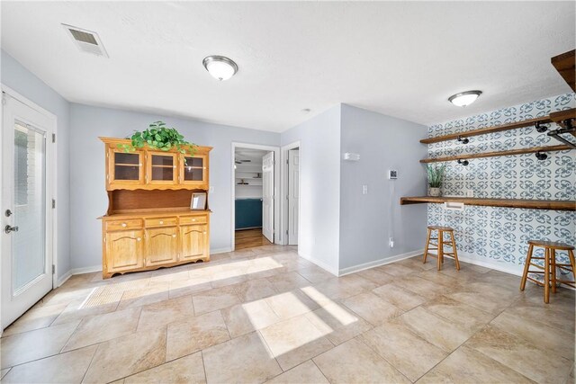 interior space featuring wallpapered walls and baseboards