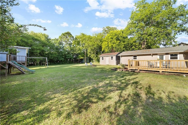 view of green lawn with a playground, a deck, and view of scattered trees