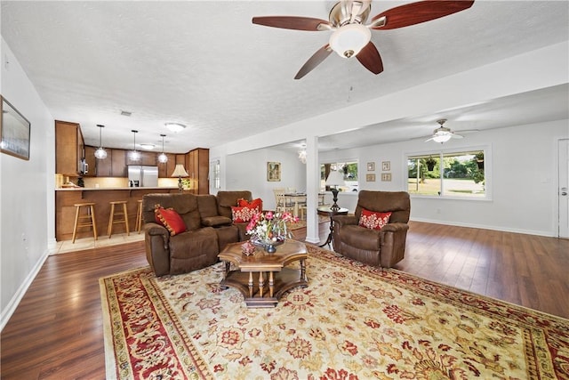 living room featuring a ceiling fan, baseboards, and dark wood-type flooring