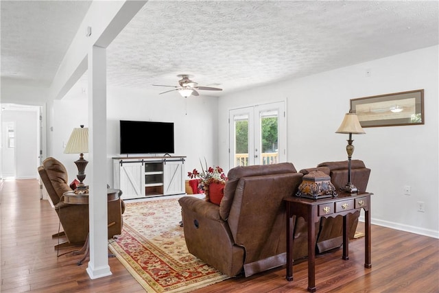 living room featuring dark wood-type flooring, a ceiling fan, french doors, baseboards, and a textured ceiling