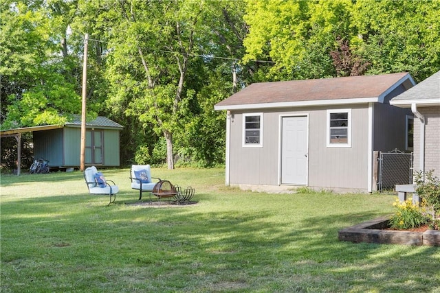 view of green lawn with a storage shed, an outbuilding, and an outdoor fire pit