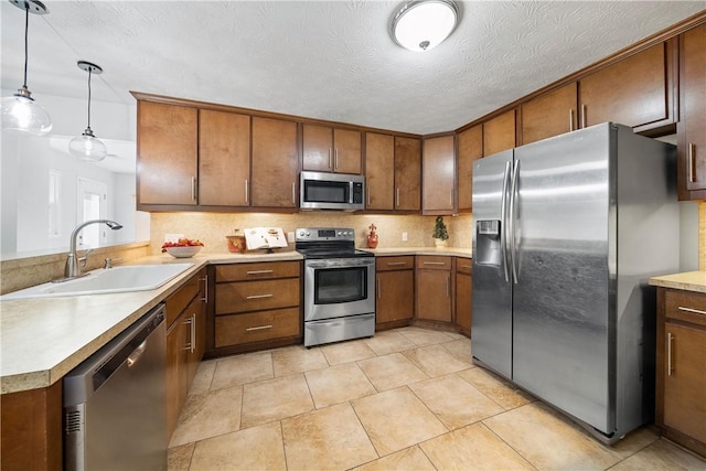 kitchen featuring a sink, brown cabinetry, light countertops, appliances with stainless steel finishes, and decorative backsplash