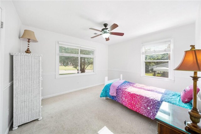 carpeted bedroom with multiple windows, a ceiling fan, and baseboards