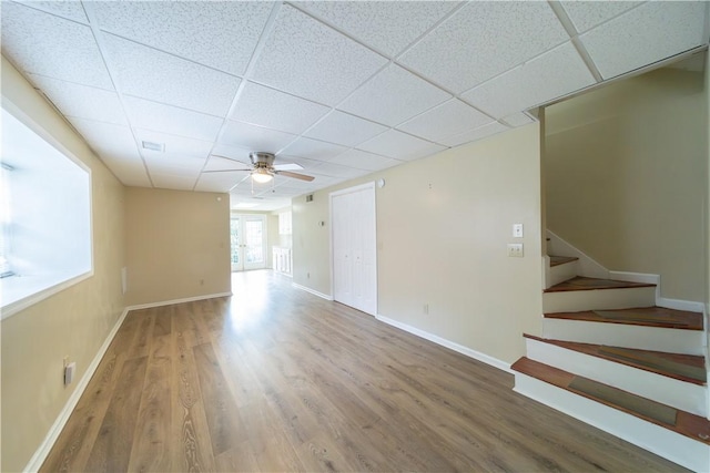 spare room with stairs, a drop ceiling, and wood finished floors