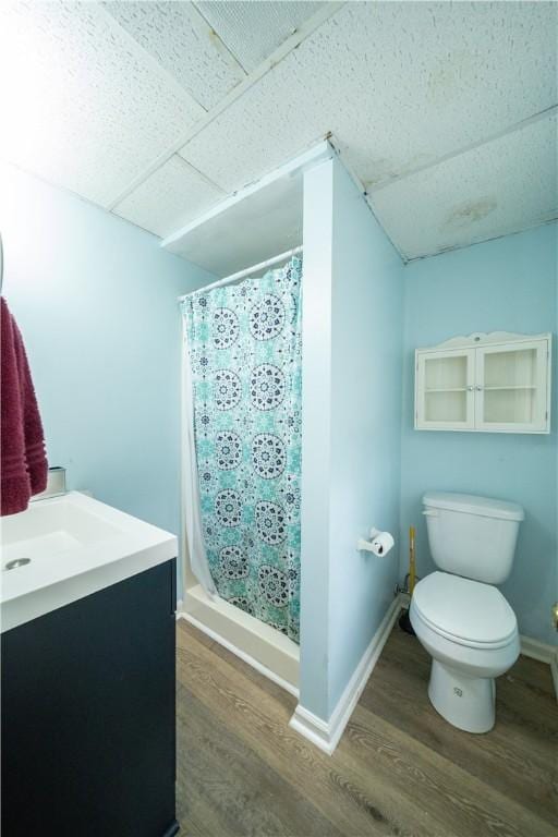 bathroom with baseboards, a shower stall, toilet, and wood finished floors