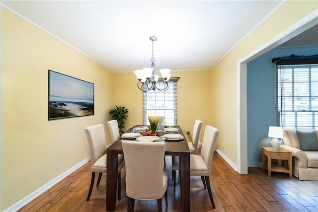 dining area with a chandelier, wood finished floors, a wealth of natural light, and baseboards