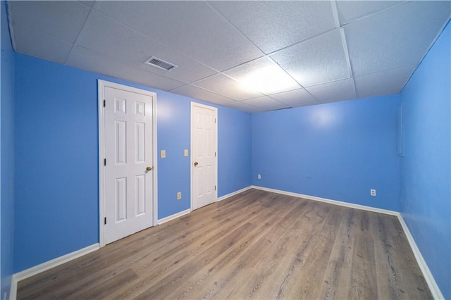 unfurnished room with baseboards, visible vents, and wood finished floors