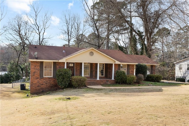 view of front facade featuring a front yard, central AC unit, and brick siding