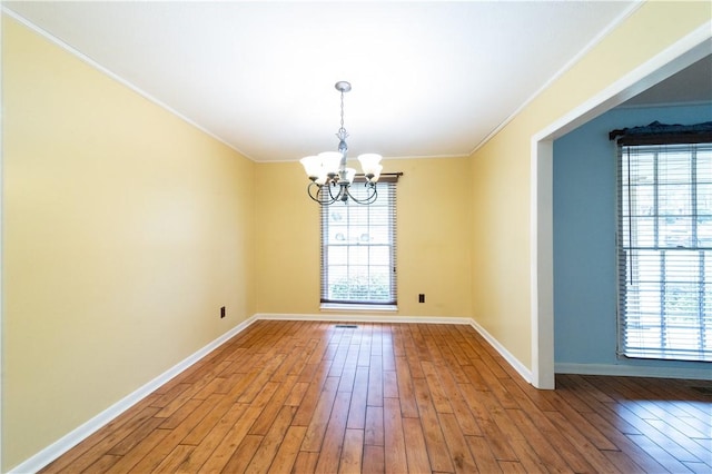 unfurnished dining area featuring a chandelier, ornamental molding, light wood-style flooring, and baseboards