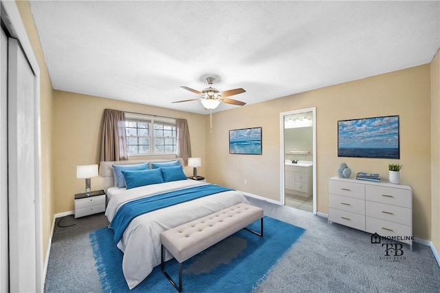 bedroom featuring a closet, carpet flooring, ceiling fan, ensuite bath, and baseboards