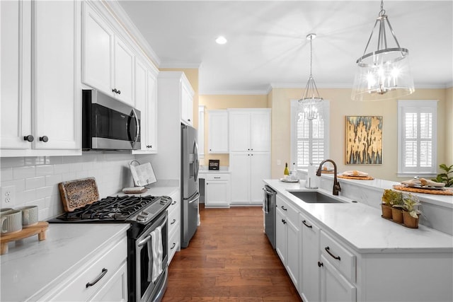 kitchen with sink, white cabinetry, decorative light fixtures, appliances with stainless steel finishes, and light stone countertops