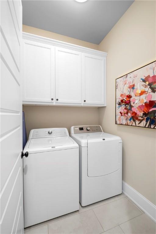 laundry room with cabinets, light tile patterned floors, and independent washer and dryer