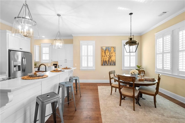 dining area featuring sink, crown molding, a healthy amount of sunlight, and hardwood / wood-style flooring