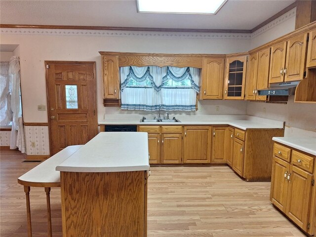 2521 28th Ave, Lanett, AL 36863 - kitchen featuring light wood-style flooring, a kitchen breakfast bar, under cabinet range hood, glass insert cabinets, and a wainscoted wall