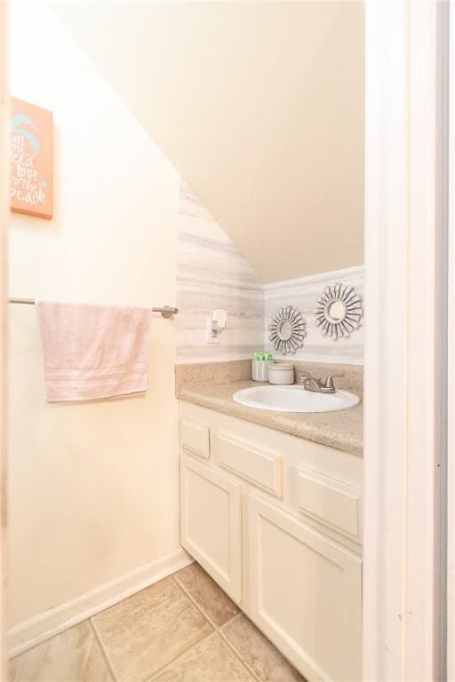 bathroom with vaulted ceiling, vanity, and tile patterned flooring