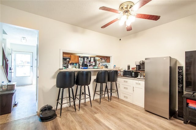 bar with freestanding refrigerator, light wood-style flooring, and ceiling fan