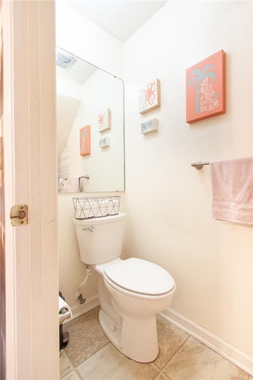 half bath with tile patterned flooring, toilet, and baseboards