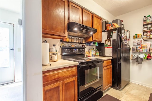 kitchen featuring under cabinet range hood, brown cabinetry, light countertops, and black appliances