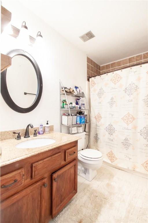 bathroom featuring toilet, vanity, curtained shower, visible vents, and tile patterned flooring