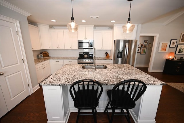 kitchen with white cabinetry, a breakfast bar, a center island with sink, visible vents, and appliances with stainless steel finishes