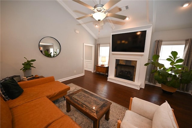 living area with vaulted ceiling, a tile fireplace, a ceiling fan, wood finished floors, and visible vents