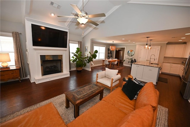 living room featuring dark wood finished floors, visible vents, a tiled fireplace, and a ceiling fan