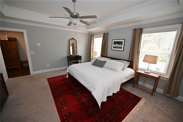 bedroom with a tray ceiling, crown molding, a ceiling fan, light carpet, and baseboards