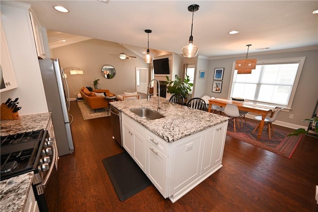 kitchen with a sink, appliances with stainless steel finishes, a center island with sink, dark wood-style floors, and ceiling fan