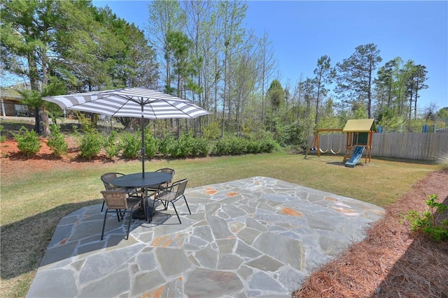 view of patio with fence, outdoor dining area, and a playground